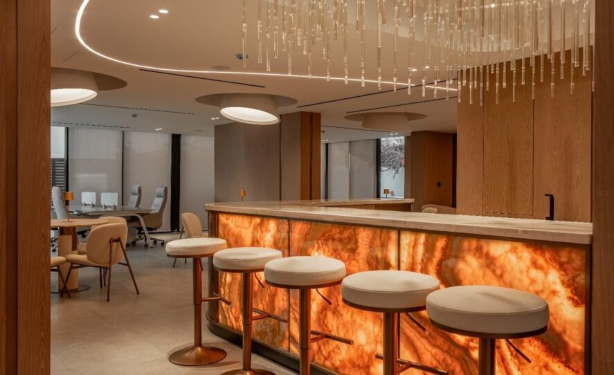 MGS Sales Office Villa — reception and main desk area. Backlit onyx, bespoke joinery, and a custom chandelier designed and delivered as one integrated package. Spazio Interior Decoration LLC