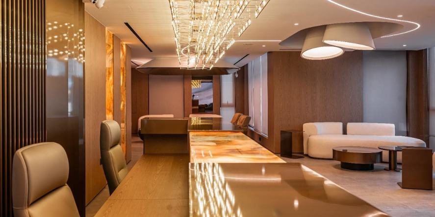 The hospitality bar and open presentation area within the MGS Sales Office — backlit onyx counter, custom chandelier, and working zones visible in the background. Each zone is designed and built as one coordinated brief. | Spazio Interior Decoration LLC